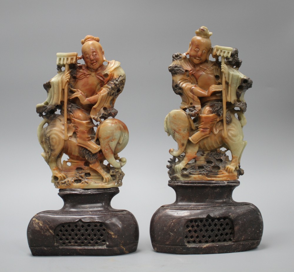 A pair of Chinese soapstone carvings depicting figures riding upon elephants, height 19cm, height with bases 27cm